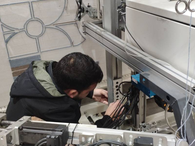Engineers receiving hands-on robotic tufting machine training to improve production efficiency
